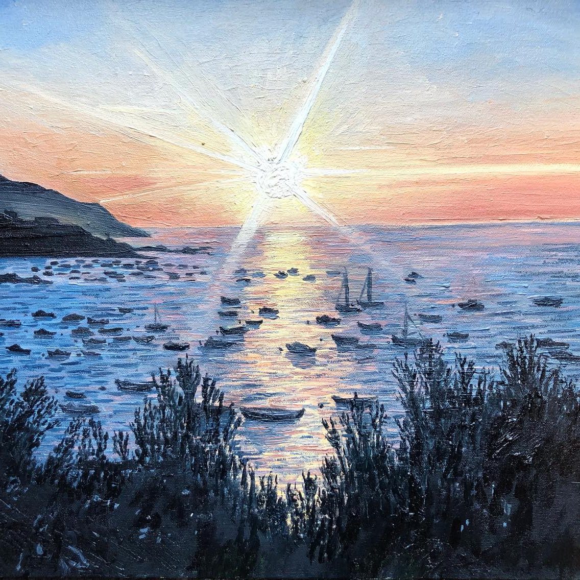 Sunset over a calm sea with boats, framed by coastal hills and sparkling water.