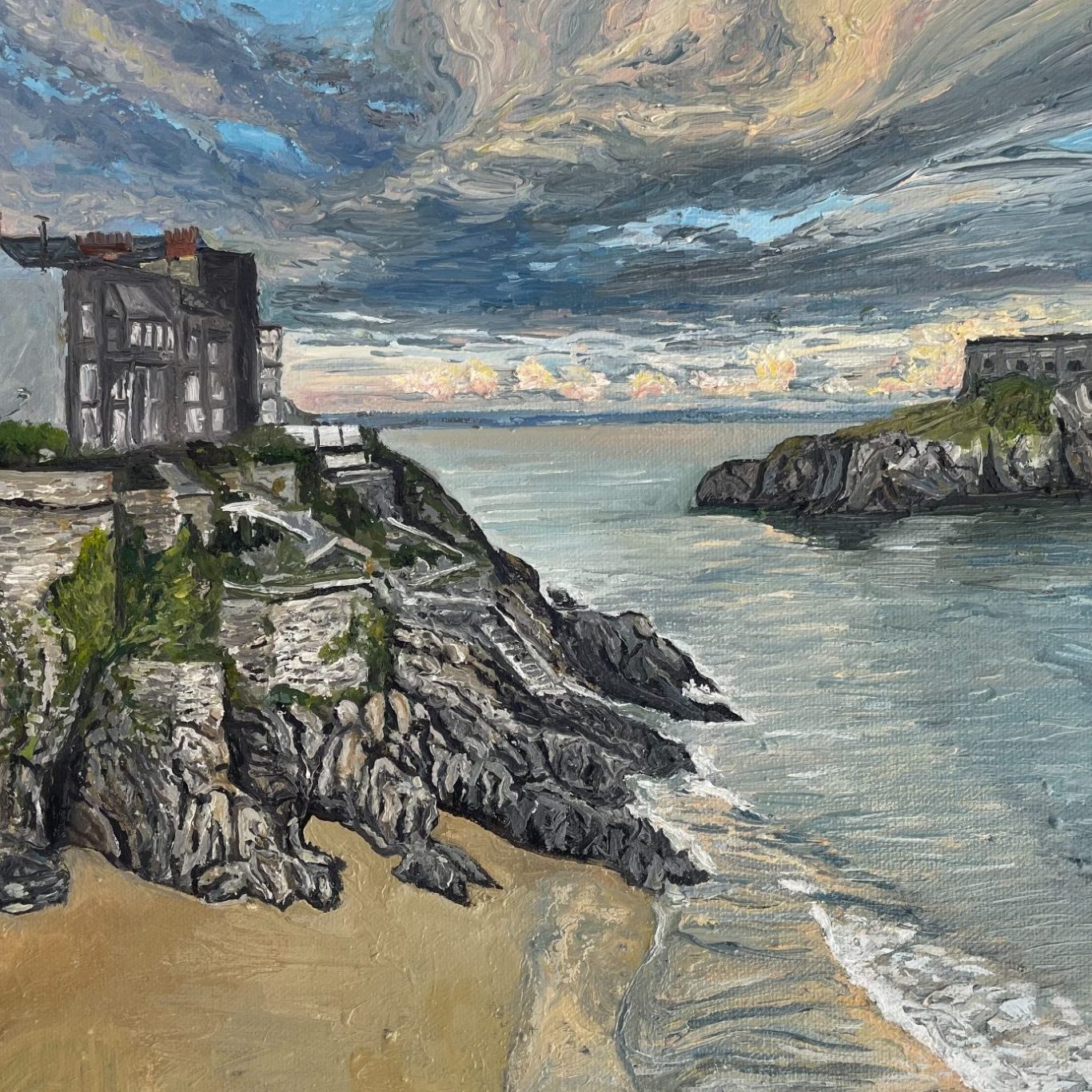 Tenby Castle scene with rocky shore, buildings, and a cloudy sky over the water.