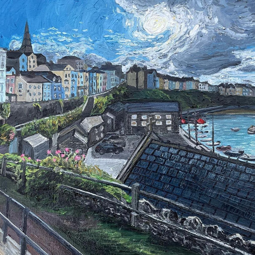 Sunset over Tenby Coastal village with colourful houses, boats in the bay, and a cloudy sky.